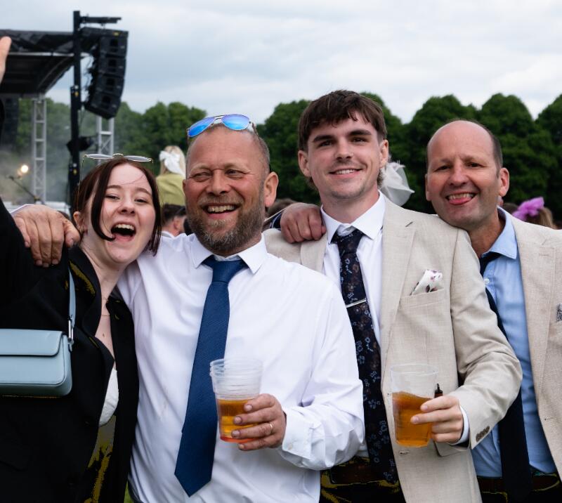 A group of race goers at Worcester Races poses in front of the stage