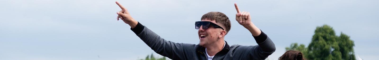 A race goer at Worcester races on the shoulders of his friends in the crowd.