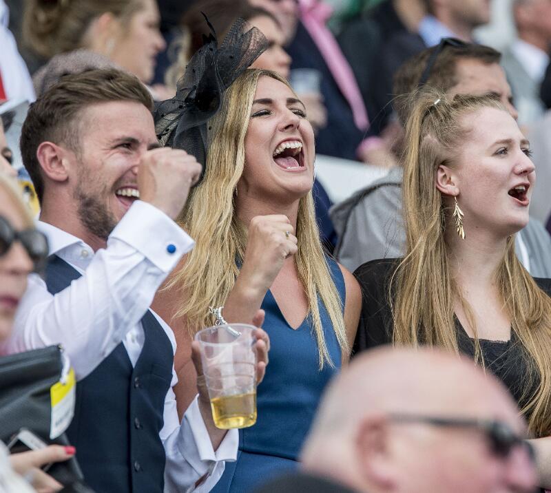 A group of race goers cheering for their horse.