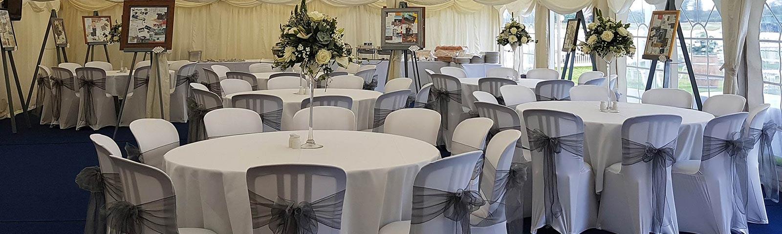 An array of large round tables decorated in white with flowers sat in the middle of each.  All inside our outdoor marquee.