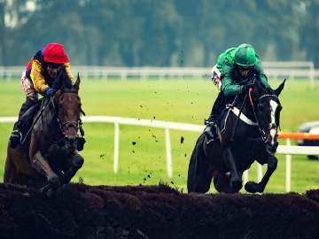 Two horses jumping a fence at Worcester Racecourse.