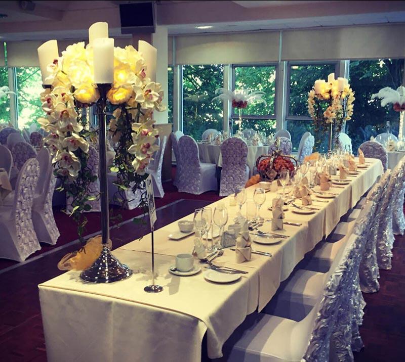 A row of connected tables decorated in a wedding theme with white and silver.