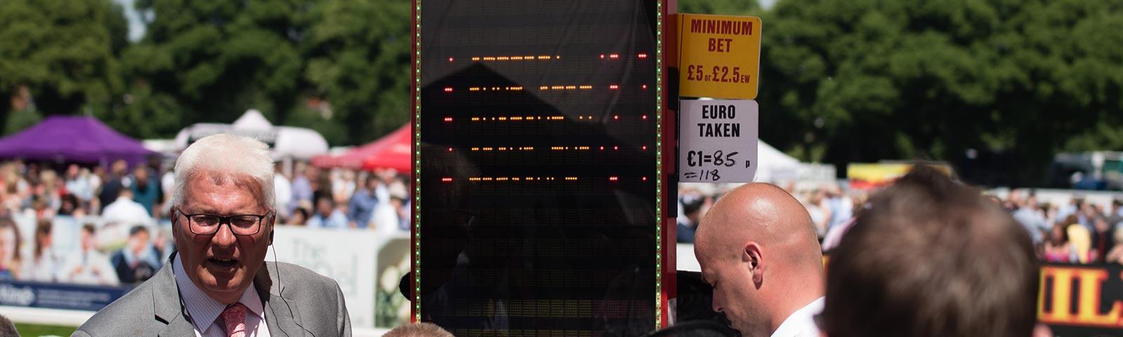 A track-side bookmaker taking bets from the crowd.